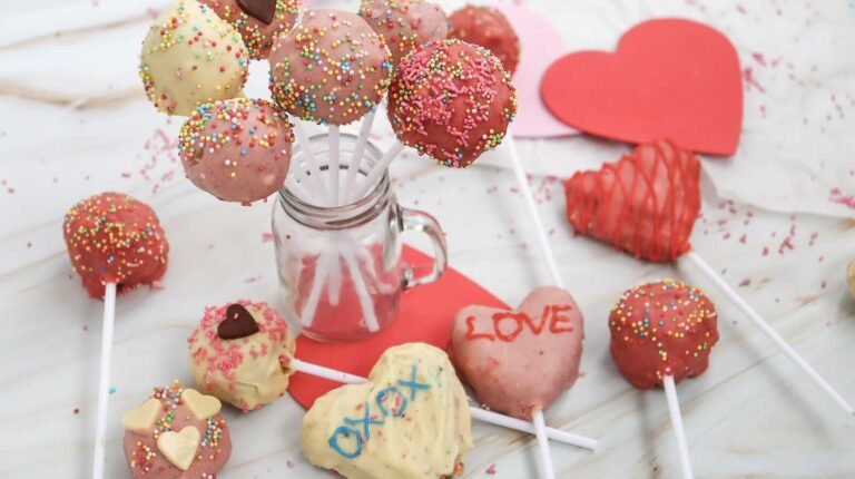 Valentine cake pops with sprinkles and heart designs on display.
