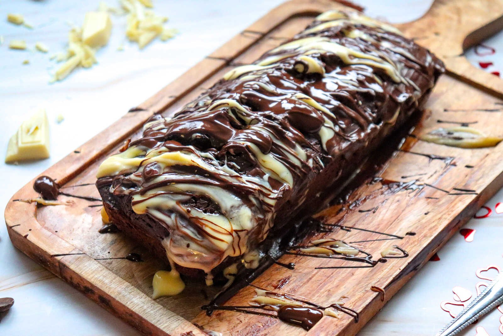 Chocolate loaf cake with chocolate and white chocolate drizzle on wooden board