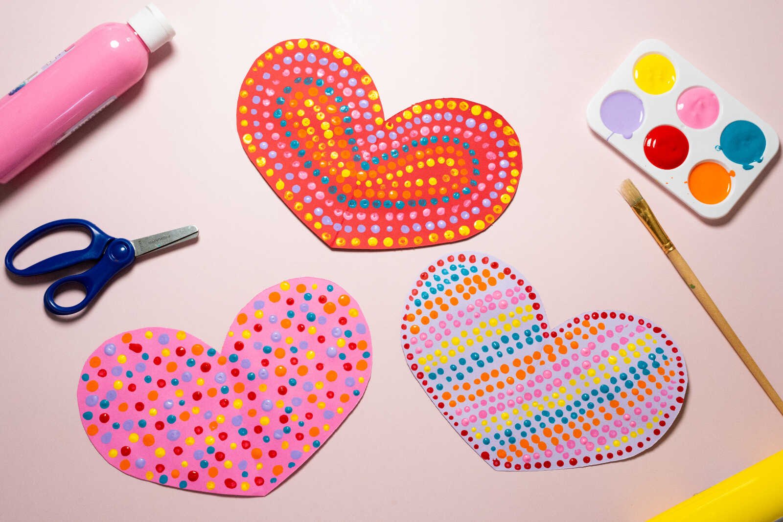 Heart Q-Tip Art with three colorful dotted hearts and craft supplies on a table.