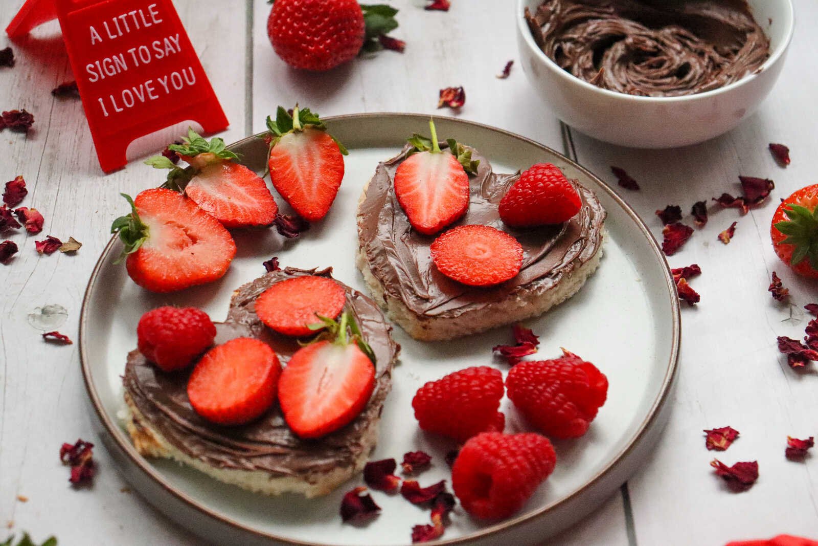 Strawberry Nutella Heart Toast topped with fresh strawberries and raspberries on a plate.